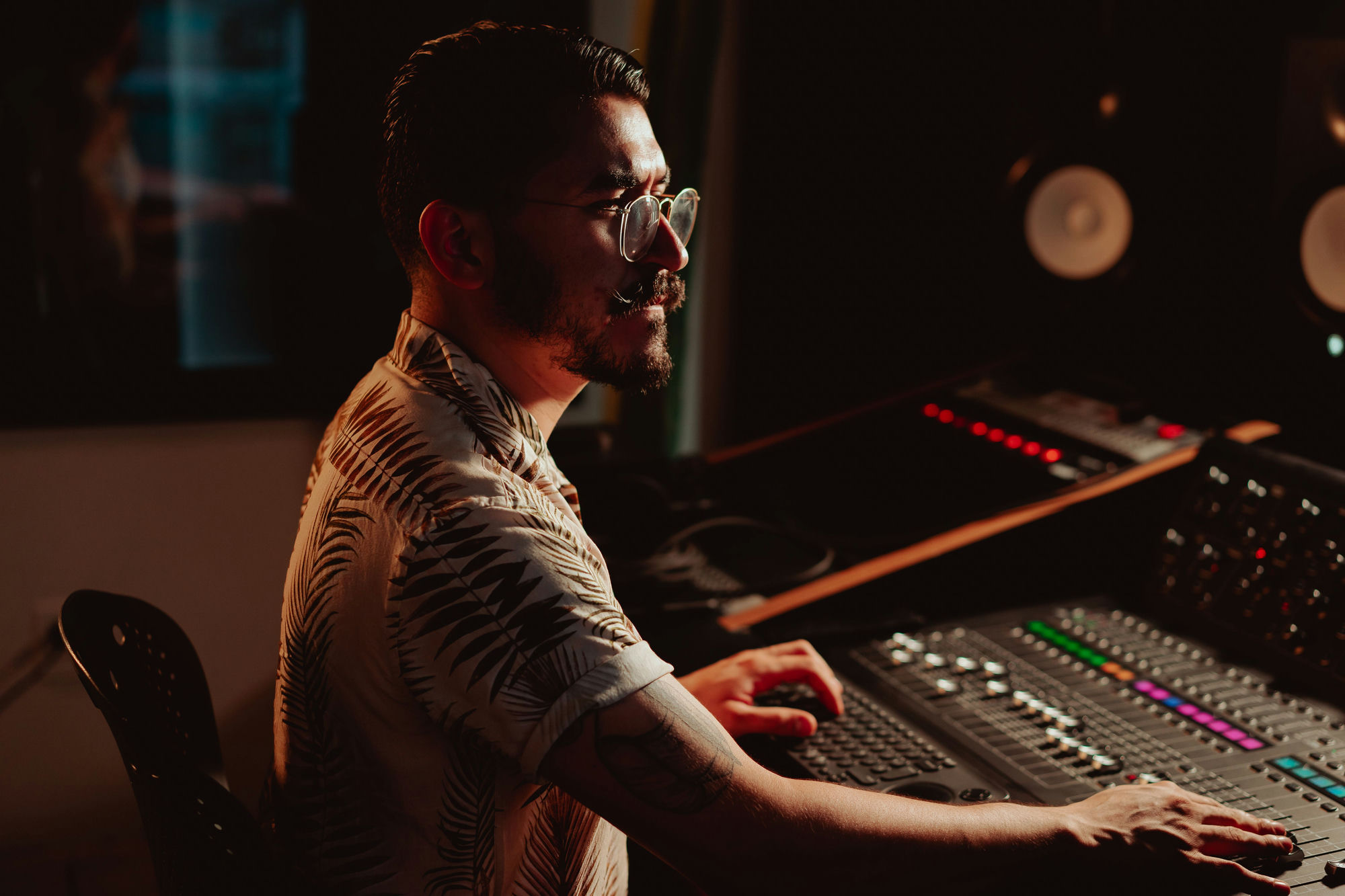 A podcaster at the mixing desk in a warmly lit studio